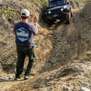 A man guiding a vehicle down a steep dirt path